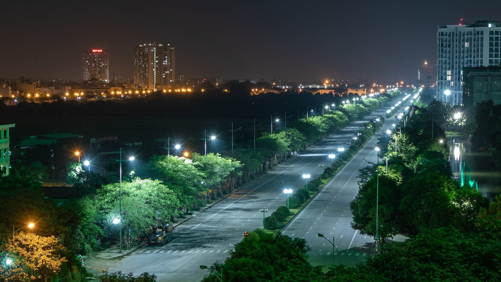 green trees near city buildings during night time that emits light pollution